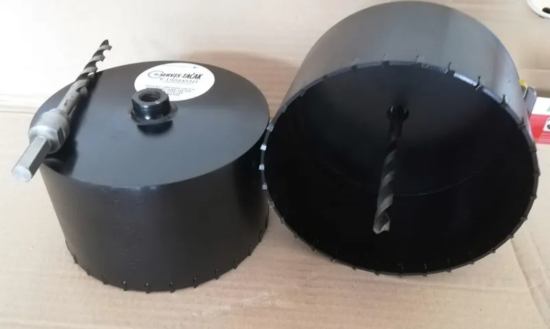 Two black core bits for drilling plastic with a centre drill, one with a SERVIS-TAČAK label